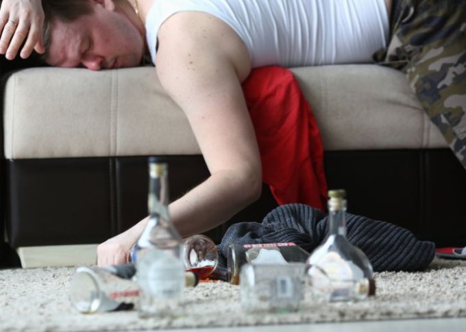 Kolejny etap alkoholizmu u mężczyzny śpiącego na kanapie po wypiciu kilku butelek alkoholu
